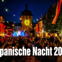 Spanische Nacht 2026 in Schlüsselfeld. Menschen feiern auf dem Marktplatz. Im Hintergrund das Stadttor von Schlüsselfeld und das Rathaus in bunter Beleuchtung