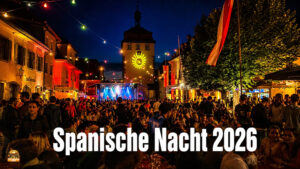 Spanische Nacht 2026 in Schlüsselfeld. Menschen feiern auf dem Marktplatz. Im Hintergrund das Stadttor von Schlüsselfeld und das Rathaus in bunter Beleuchtung