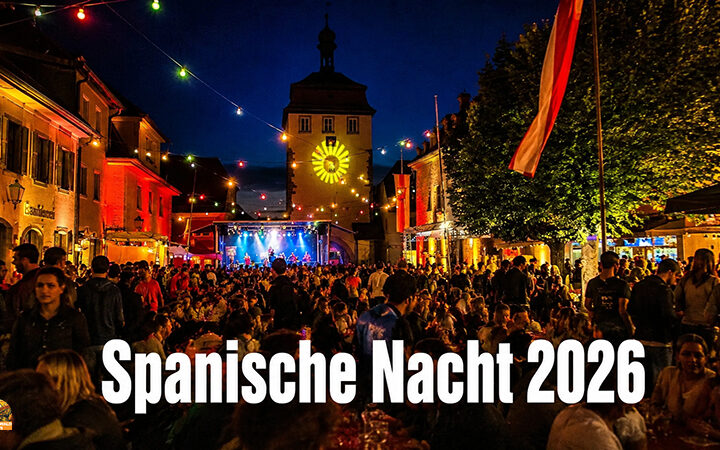 Spanische Nacht 2026 in Schlüsselfeld. Menschen feiern auf dem Marktplatz. Im Hintergrund das Stadttor von Schlüsselfeld und das Rathaus in bunter Beleuchtung